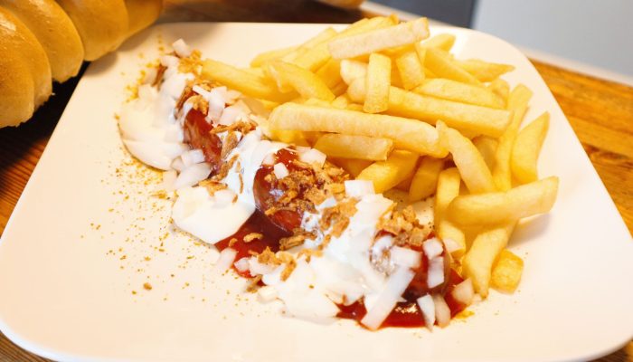 Spezialwurst mit Pommes vom Imbiss Fritz in Bielefeld: Saftige Bratwurst, verfeinert mit Ketchup, Mayonnaise und Zwiebeln, dazu knusprige Pommes – ein Klassiker!